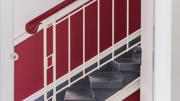 A staircase with a red wall and white handrail.