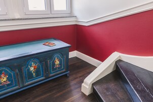 Una escalera con escalones de madera oscura y un banco azul decorado con motivos florales.