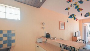 A kitchen with a wooden countertop, a sink, and a window. There are two clocks on the wall and a framed picture. - Cozy Apartment Near Beach and Shops, with Balcony and Modern Amenities (Les Sables-d'Olonne)