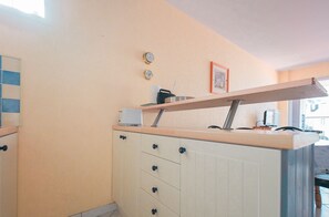 Eine Küche mit weißer Arbeitsplatte, einem Toaster, einer Kaffeemaschine und einem gerahmten Bild an der Wand.