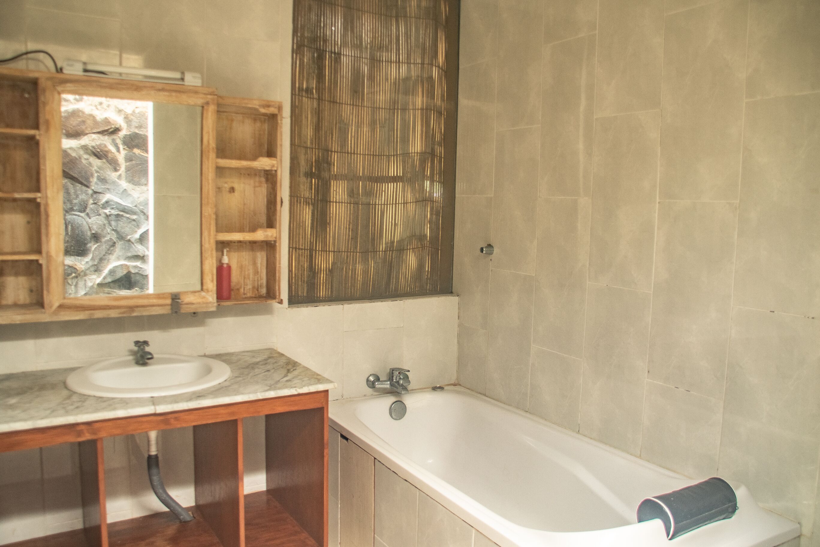 A bathroom with a wooden vanity, a sink, a bathtub, and a mirror.