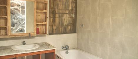 A bathroom with a wooden vanity, a sink, a bathtub, and a mirror.