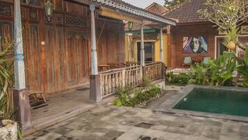 A courtyard with a pool, wooden buildings, and a mural.