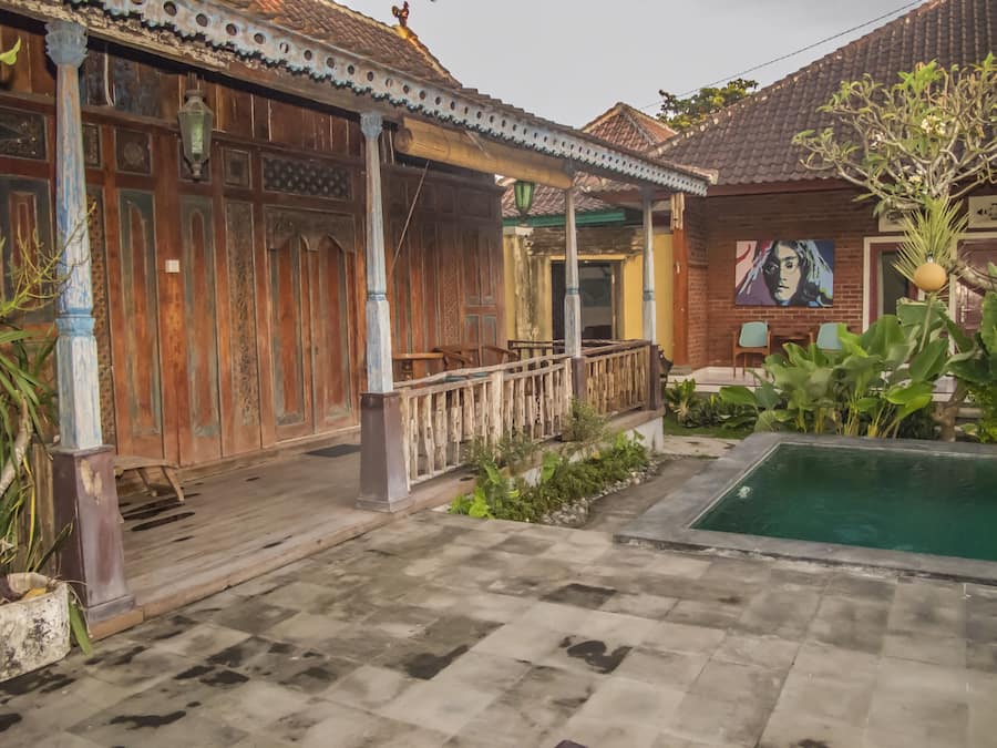 A courtyard with a pool, wooden buildings, and a mural.
