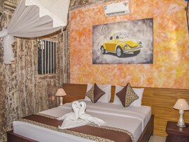 A hotel room with a bed, a painting of a car on the wall, a white canopy, and an air conditioning unit.