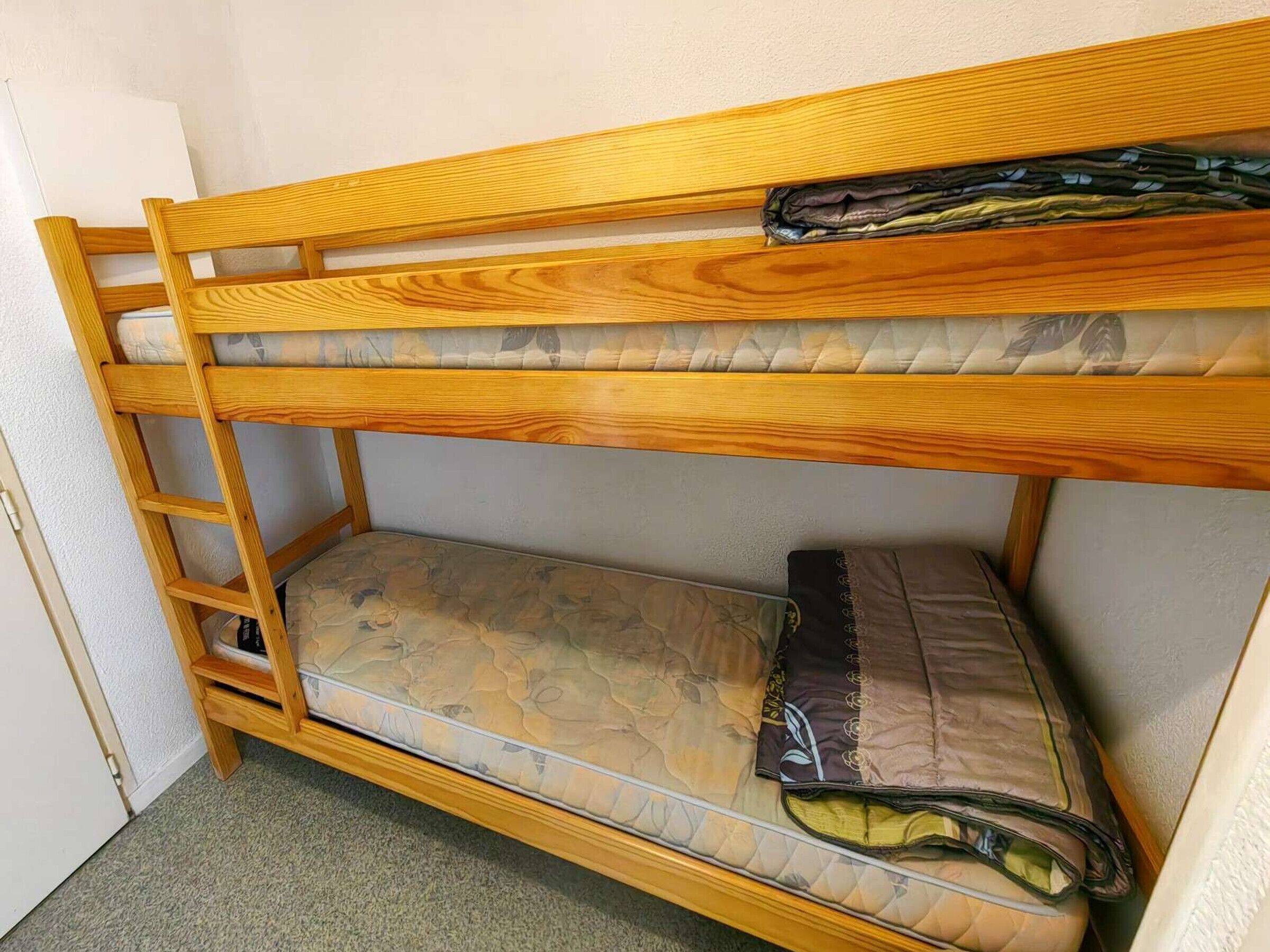 A bunk bed with a wooden frame and a mattress with a floral pattern.