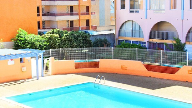 A swimming pool with a metal fence, surrounded by multi-story buildings with balconies. - 2-room apartment with pool, 4 ppl, Cap d'Agde (Cap d'Agde)