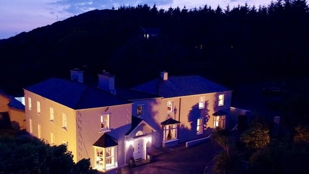 A large, multi-story house with a well-lit entrance and a driveway leading to the front door. - Clifden's premier holiday home with heated pool + sauna - sleeps 24 (Clifden)