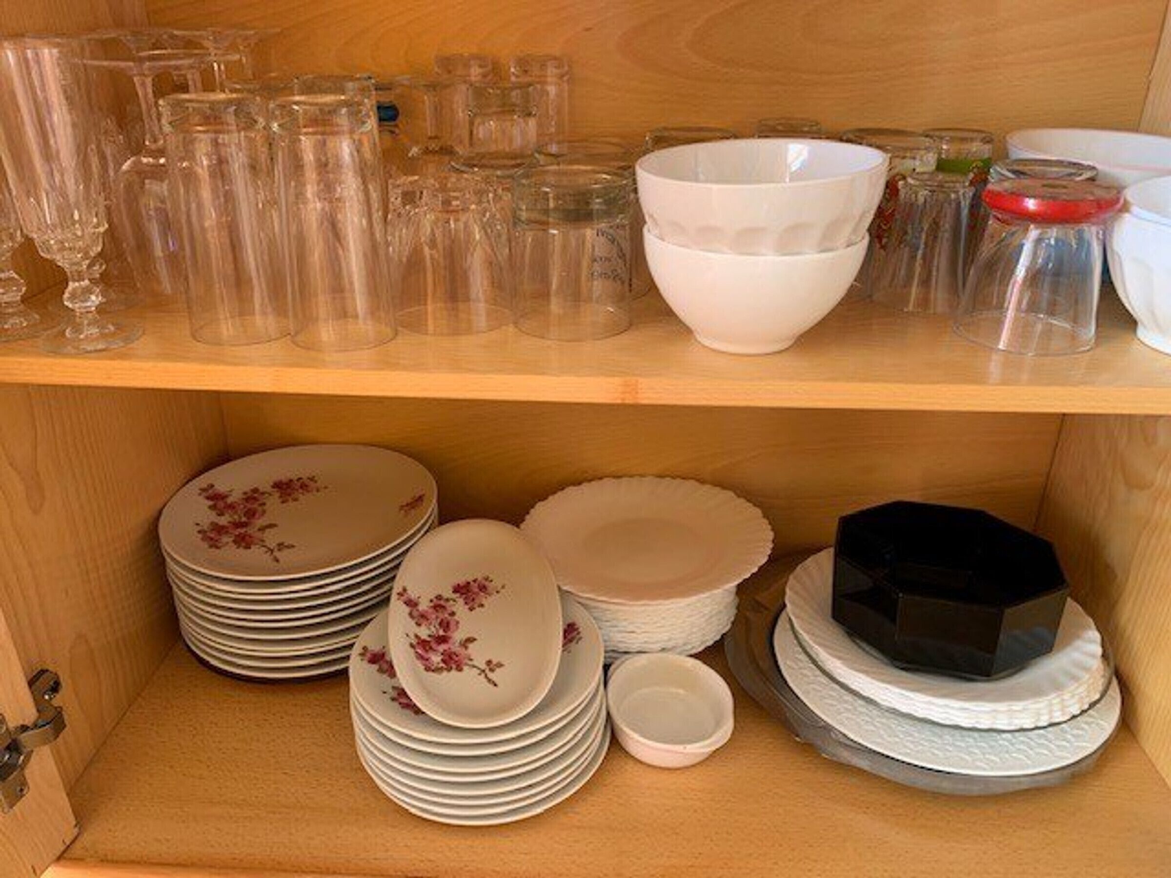 A storage area with glassware, bowls, and stacked plates.