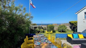 A dining area with a table set for six, yellow chairs, and a view of the sea. - Sunset Beach House, Porthleven, with panoramic sea views. Comfortably sleeps 10 (Porthleven)