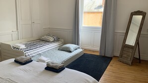A bedroom with a bed, a bench, a mirror, and a view of the outside. - A charming Domaine de La Béchetière, located 2h15 from Paris! (Parcé-sur-Sarthe)