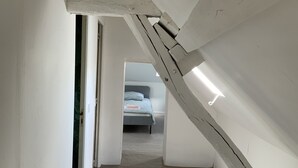 A narrow hallway with a sloped ceiling leading to a bedroom. - A charming Domaine de La Béchetière, located 2h15 from Paris! (Parcé-sur-Sarthe)
