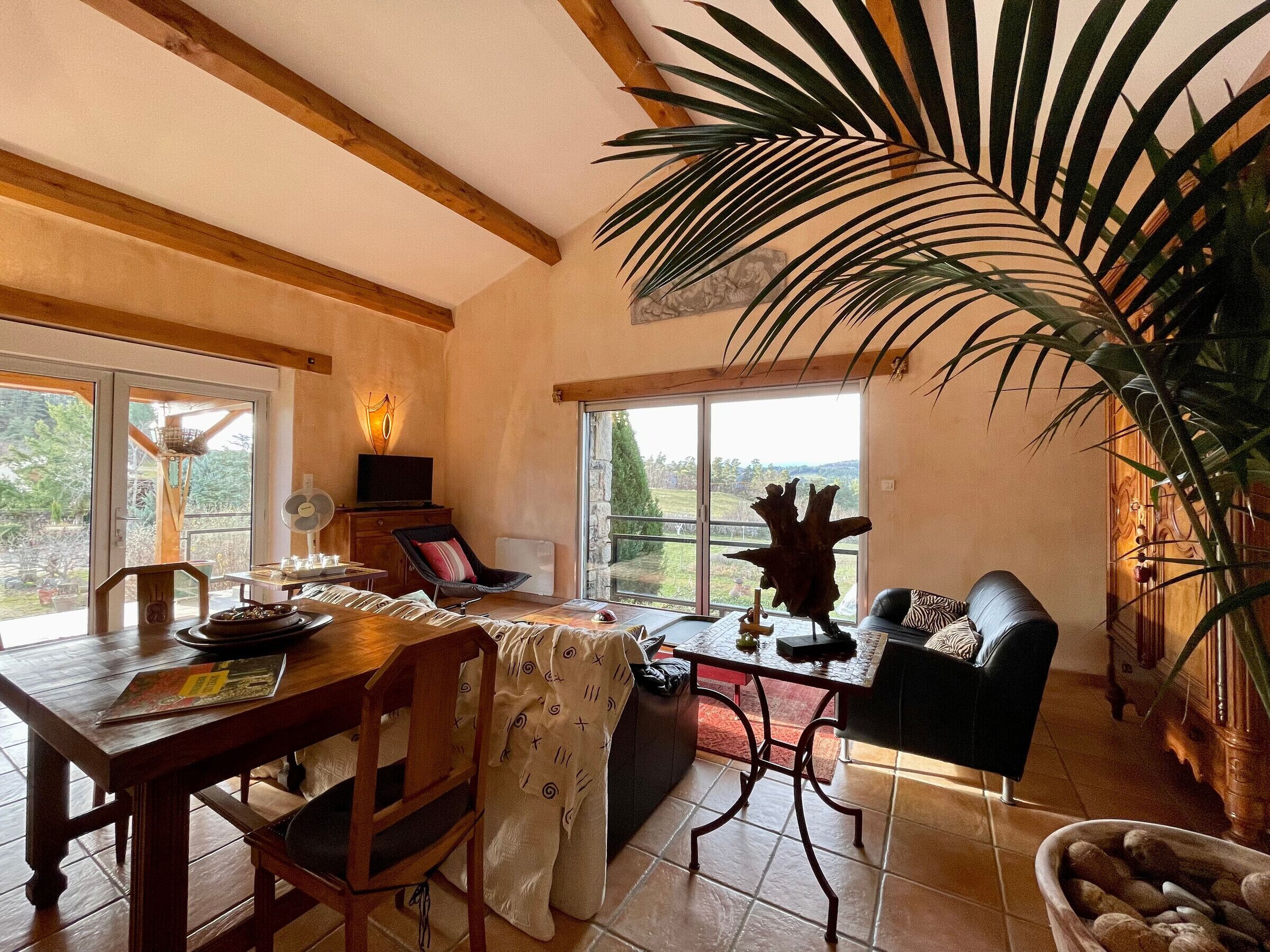 A dining area with a wooden table, chairs, and a large window offering a view of the outdoors.
