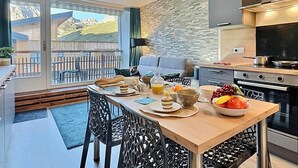 A modern kitchen with a dining area, a large window with a view of mountains, and a balcony with outdoor furniture. - Tignes - Apartment for 4, south balcony, TV Orange, wifi (Tignes)