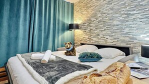 A hotel room with a bed, a teddy bear, a lamp, and a stone wall. - Tignes - Apartment for 4, south balcony, TV Orange, wifi (Tignes)