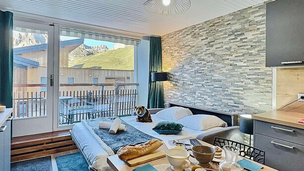 A modern hotel room with a bed, breakfast table, and a view of a mountainous landscape. - Tignes - Apartment for 4, south balcony, TV Orange, wifi (Tignes)