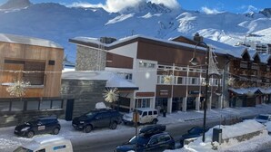 A modern building with a stone facade and a wooden section, surrounded by snow-covered mountains. - Tignes - Apartment for 4, south balcony, TV Orange, wifi (Tignes)