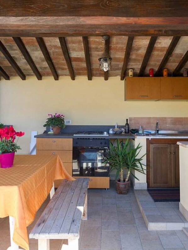 A compact kitchen with wooden cabinets, a built-in oven, and a dining area with a bench and table.