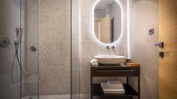 Une salle de bain moderne avec une douche à l’italienne, un miroir rond et un meuble-lavabo en bois foncé.