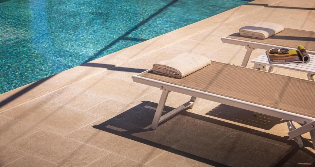 Zona de piscina con sillones reclinables y toallas.