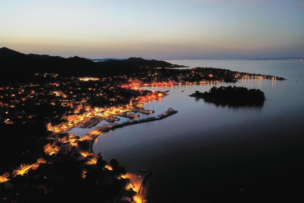 A coastal town at dusk with illuminated buildings and a marina.