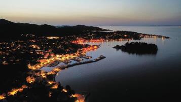 A coastal town at dusk with illuminated buildings and a marina.