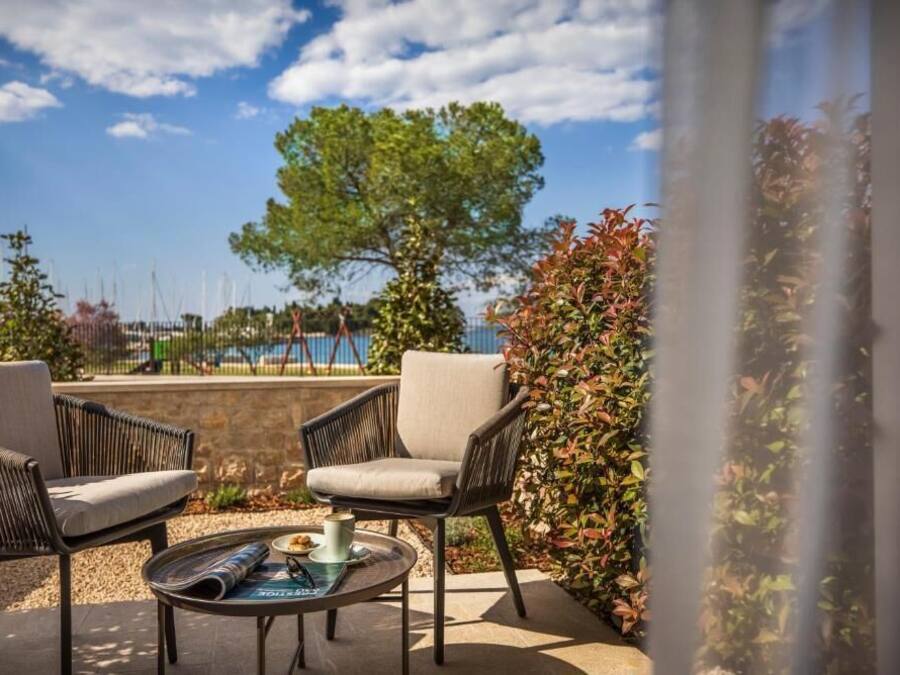 Un área de estar al aire libre con dos sillas y una mesa, con vista a un cuerpo de agua y un árbol.
