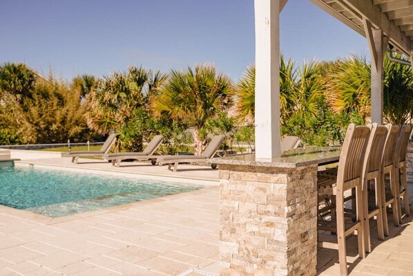 A pool area with lounge chairs and a covered seating area.