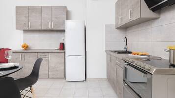 The dining table seamlessly connects with the modern kitchen, equipped with wooden cabinets, a stove, and sleek appliances.
