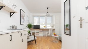Une cuisine moderne avec des meubles blancs, un coin repas avec une chaise blanche et une petite table ronde agrémentée d’une plante.
