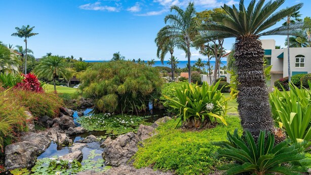 A tropical garden with a pond, palm trees, and a view of the ocean. - Tropical Paradise in Luxurious 1br, 2ba Ground Floor Unit, Garden View, Palms 801 (Kihei)