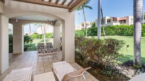 A covered outdoor seating area with a bench and lounge chairs, surrounded by greenery and palm trees. - Tropical Paradise in Luxurious 1br, 2ba Ground Floor Unit, Garden View, Palms 801 (Kihei)