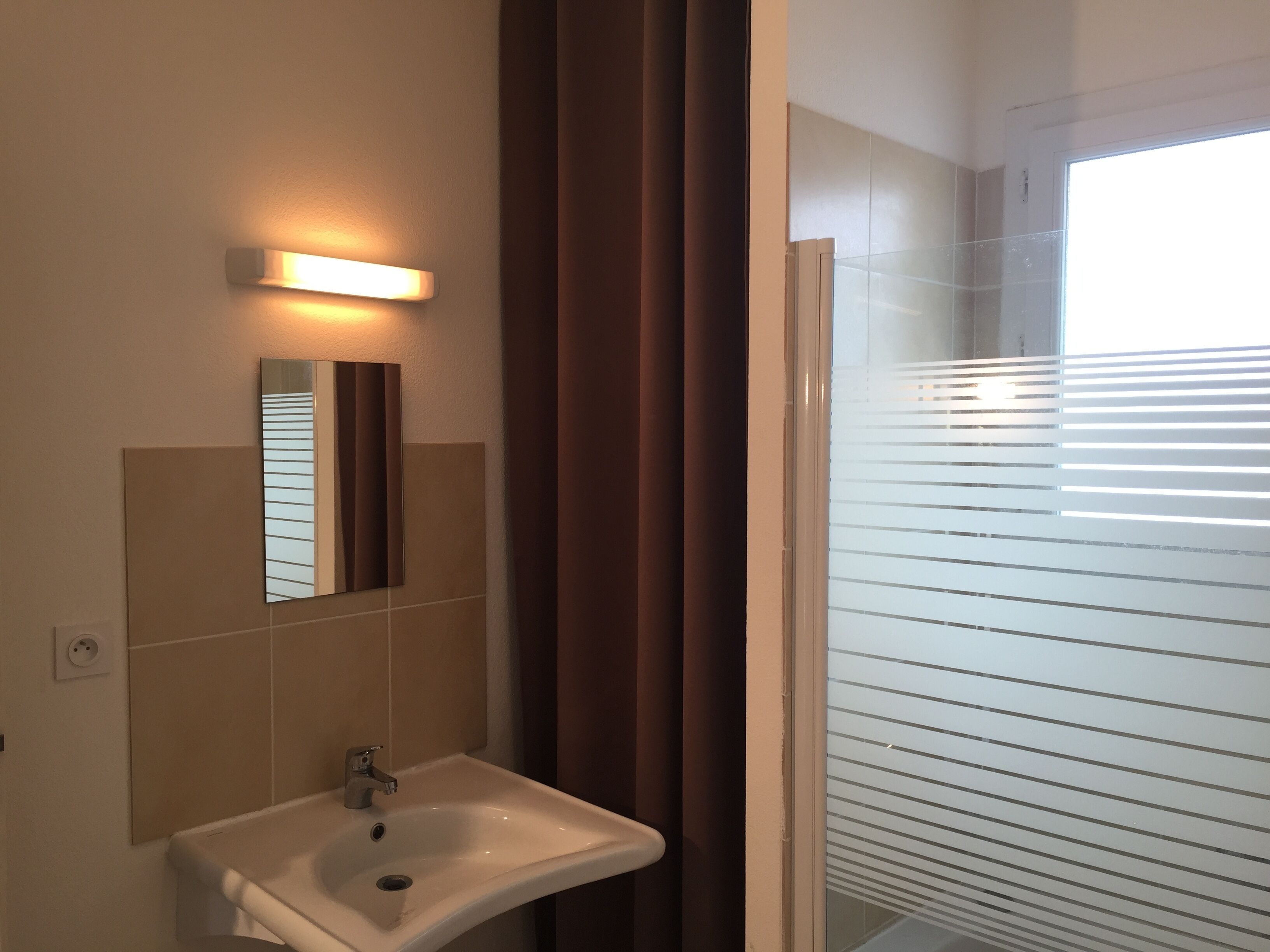 A bathroom with a sink, mirror, and shower area.