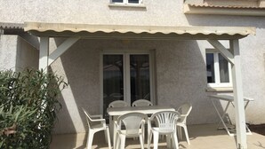 Un portico coperto con tavolo e sedie, una finestra e una porta.