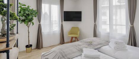 Una habitación de hotel con cama, escritorio, silla, televisor y planta en maceta.