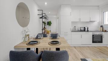 A modern kitchen with white cabinets, a microwave, and an oven.