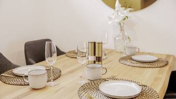 A dining table set with white plates, clear wine glasses, and a gold-colored candle holder.