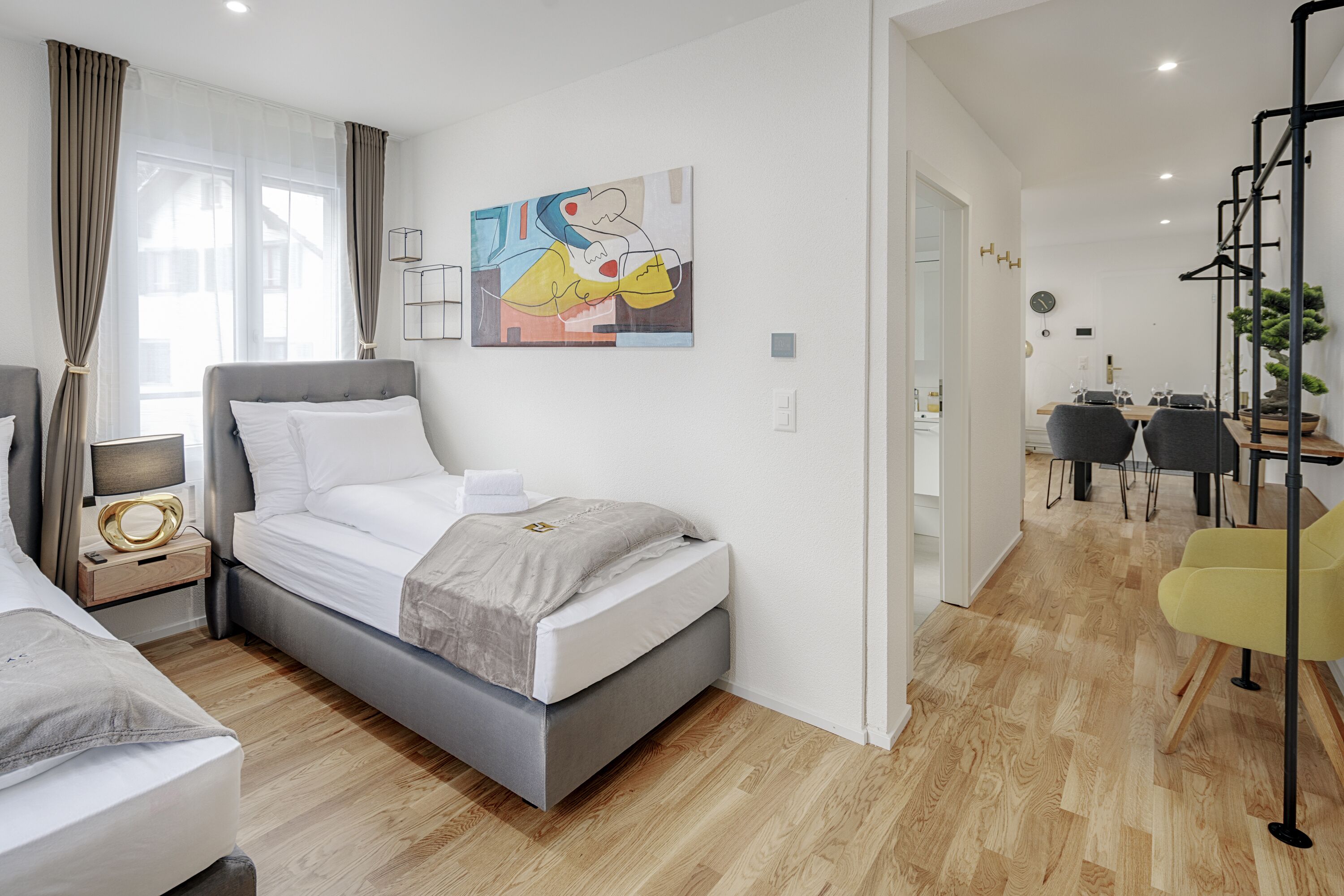 Ein modernes Schlafzimmer mit Bett, Nachttisch und Blick auf den Essbereich.