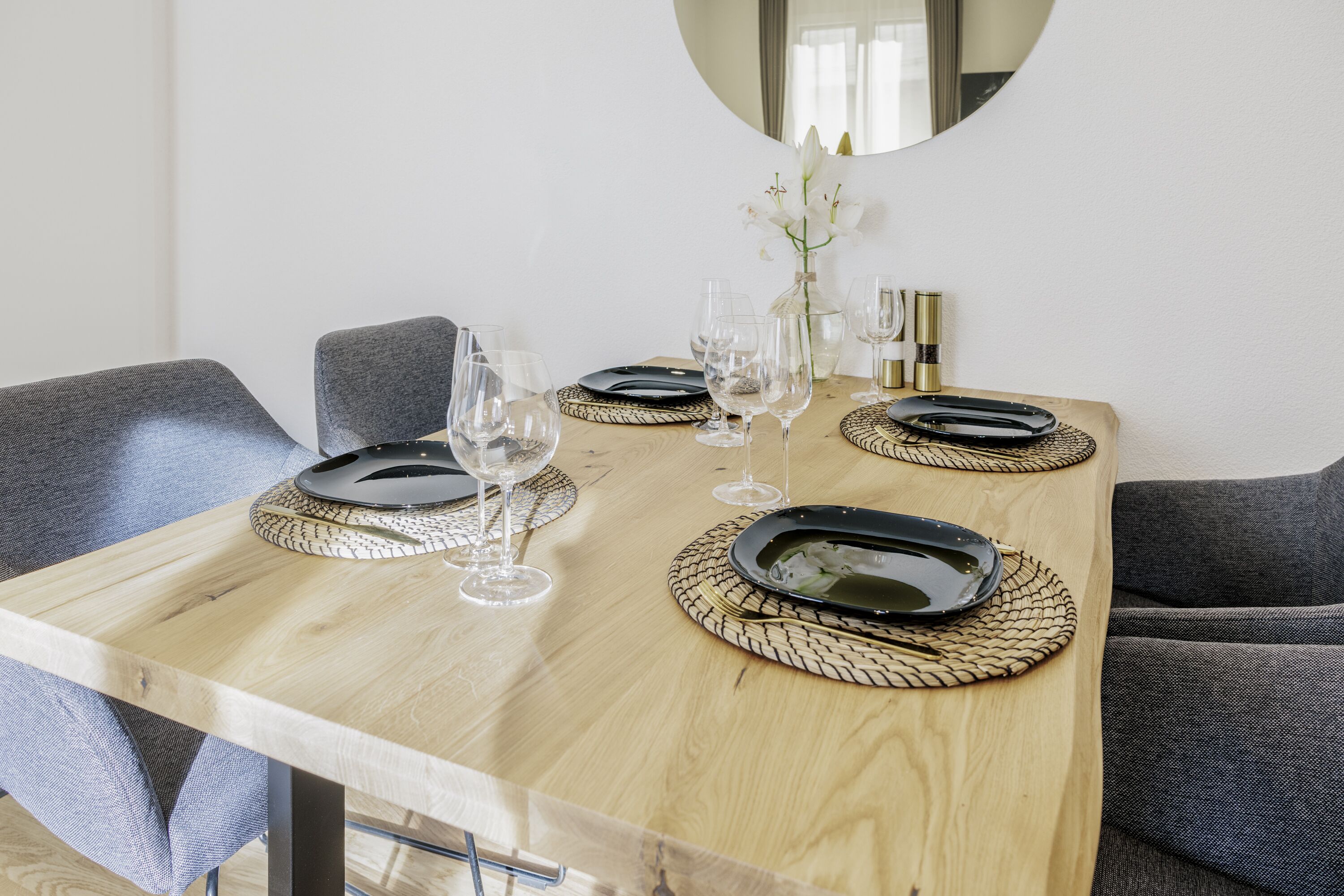 A dining table set with plates, glasses, and a vase of flowers.