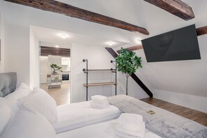 A modern bedroom with a bed, a bedside table, a plant, and a TV mounted on the wall. - VISIMO Apartments St Georgen-Strasse St Gallen - Design City Nature (St. Gallen)