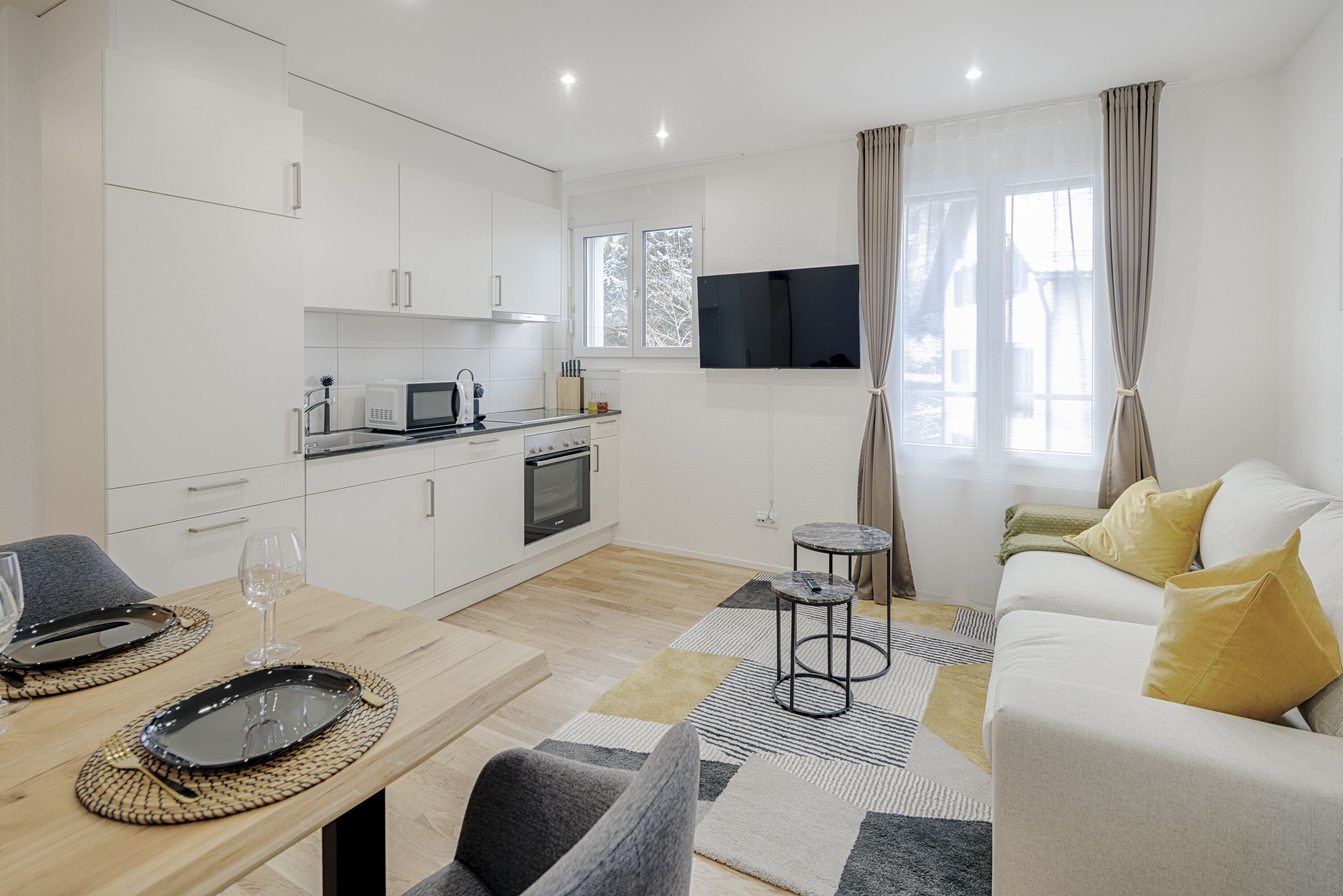 A modern living room with a sofa, coffee table, and a flat-screen TV mounted on the wall.