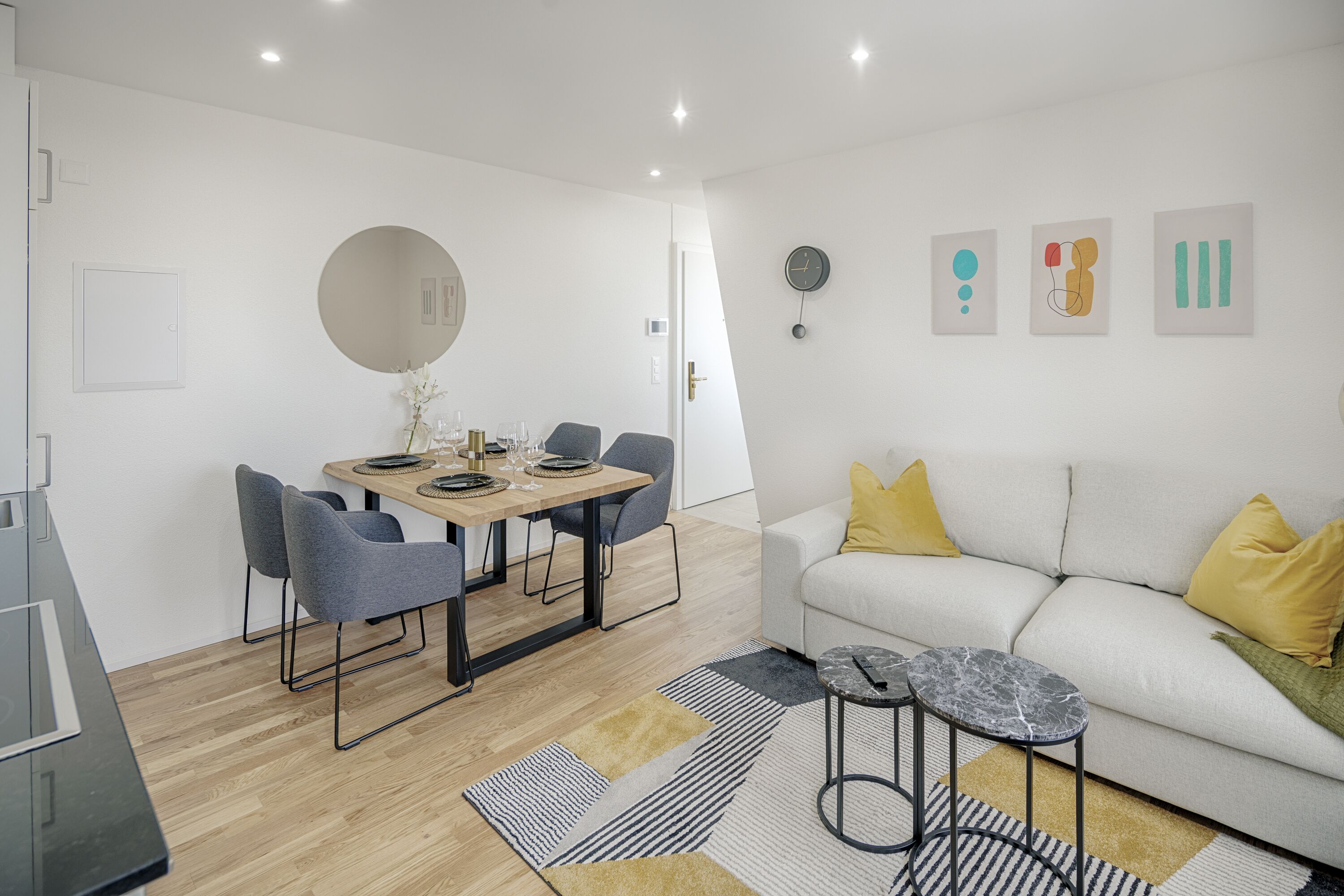 Ein modernes Wohnzimmer mit einer Couch, einem Couchtisch und einem Essbereich mit Stühlen und einem Tisch.