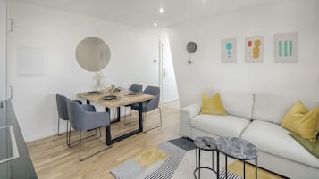 Ein modernes Wohnzimmer mit einer Couch, einem Couchtisch und einem Essbereich mit Stühlen und einem Tisch.