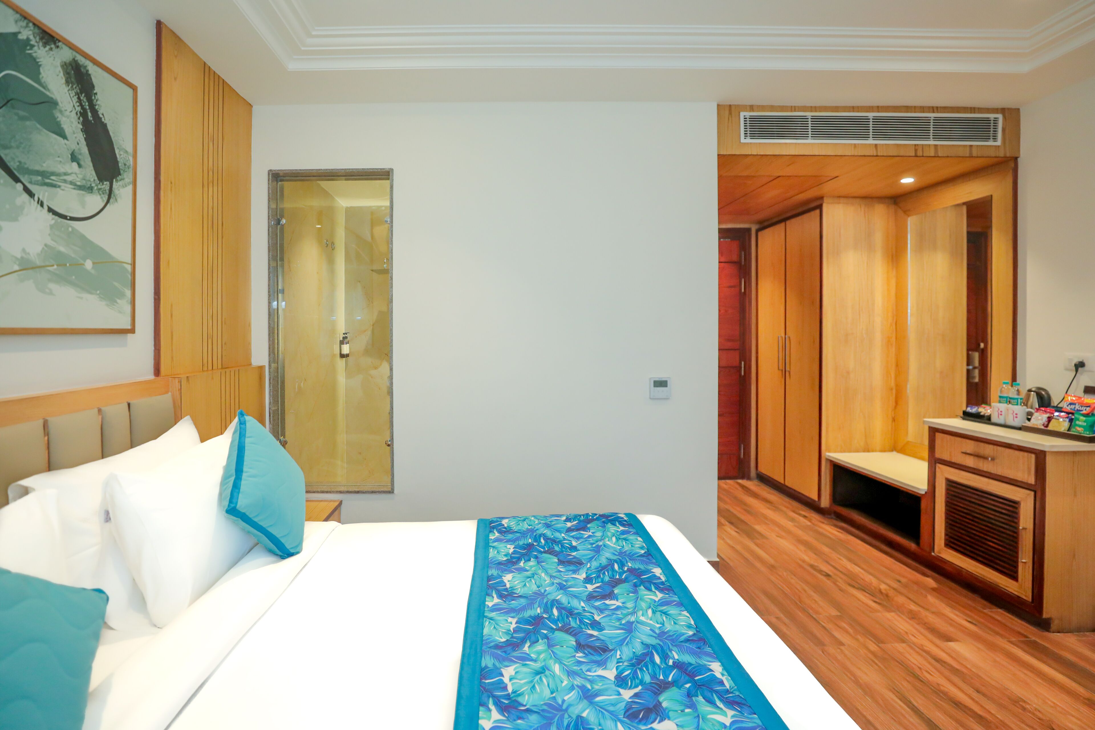 Una camera d'albergo con un letto, una scrivania, un armadio e uno spazio doccia.