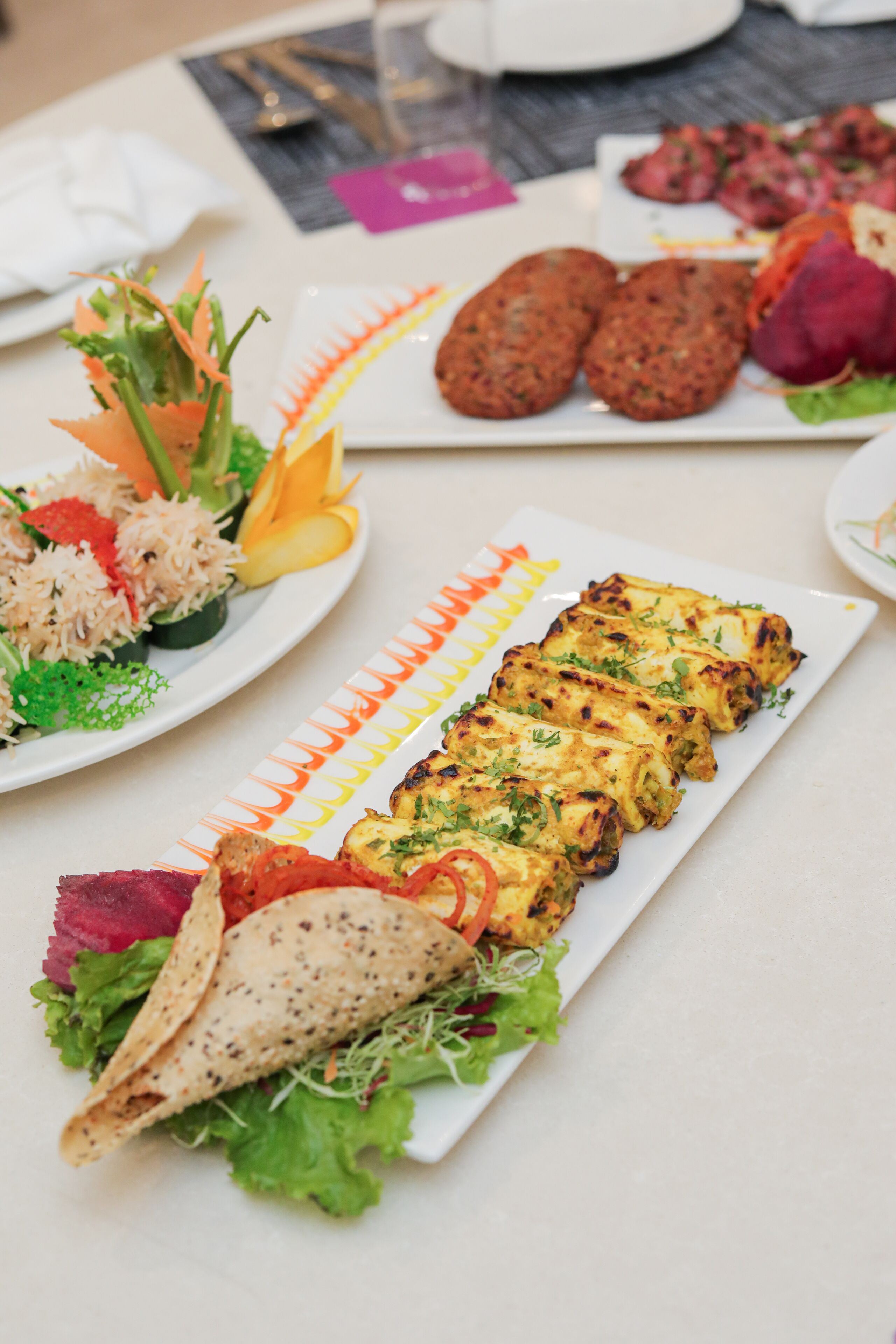 Une variété de plats sont disposés sur la table, notamment une assiette contenant du poulet grillé, des légumes et une tortilla.