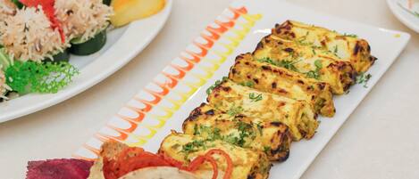 Une variété de plats sont disposés sur la table, notamment une assiette contenant du poulet grillé, des légumes et une tortilla.