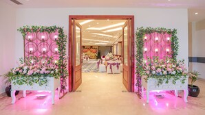 Entrada de hotel con un arco imponente, una zona de recepción con un arreglo floral y un interior bien iluminado.