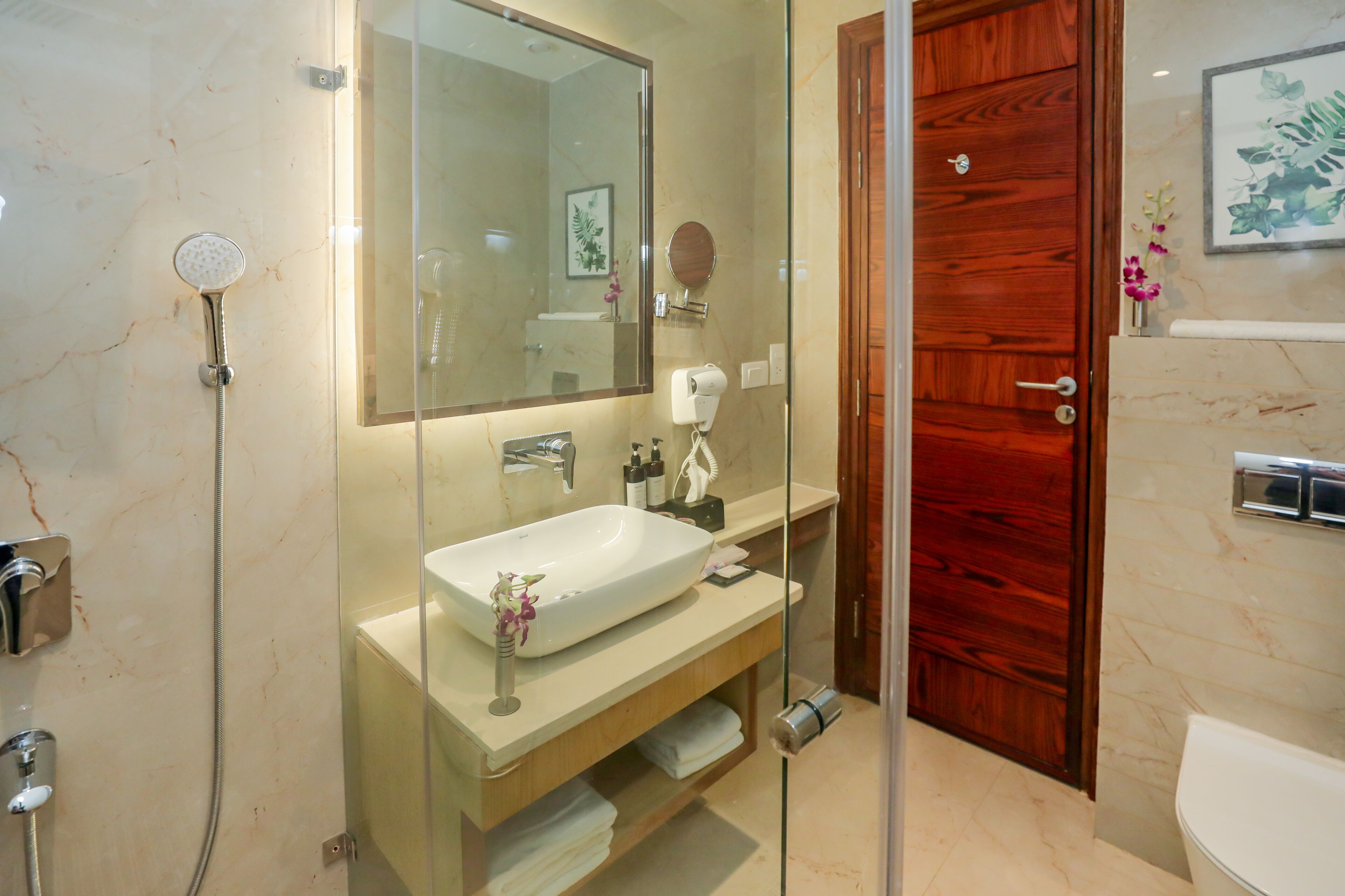 Ein modernes Badezimmer mit großem Spiegel, Waschbecken, Dusche und Holztür.
