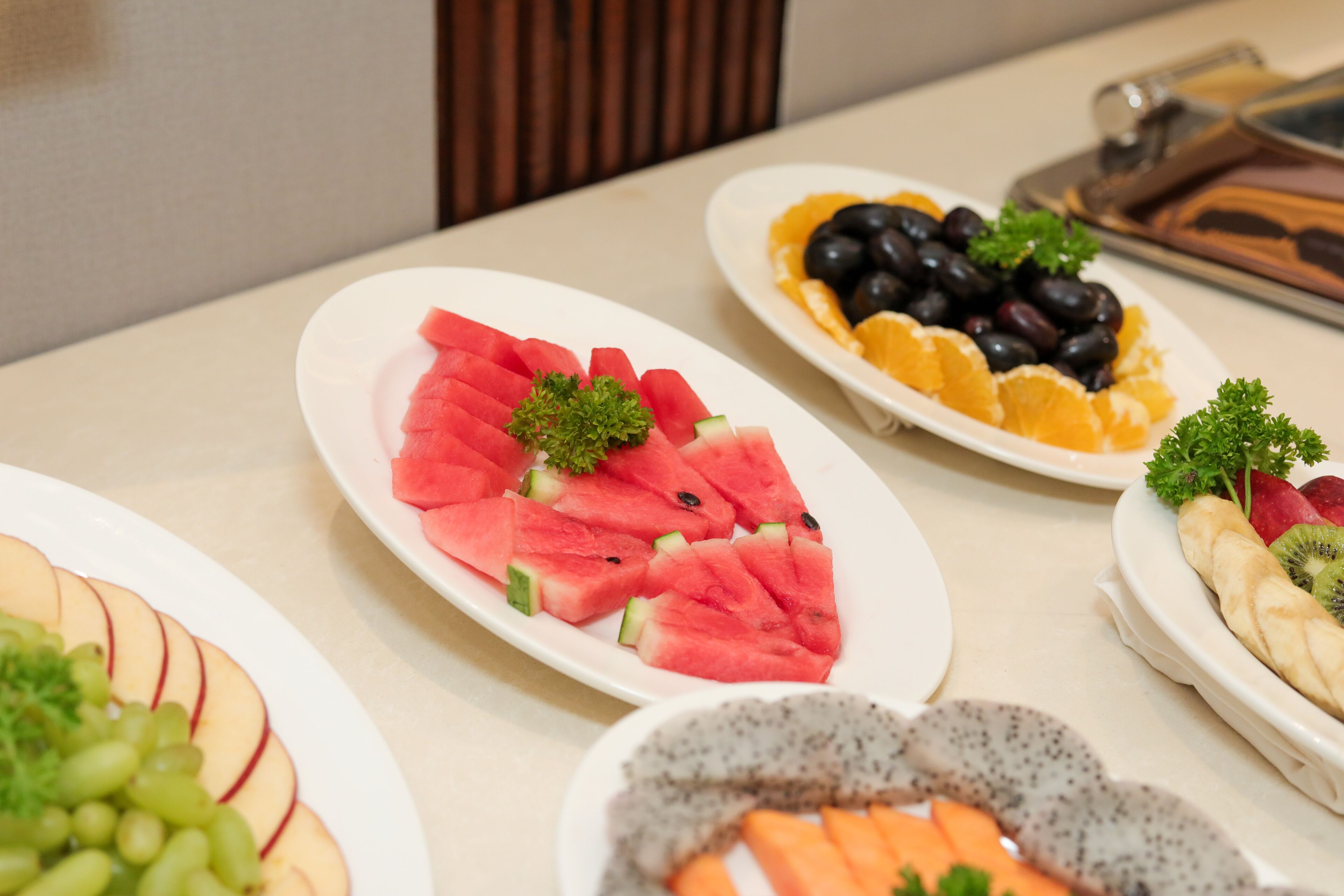 A table with various fruit platters, including watermelon, grapes, and kiwi.