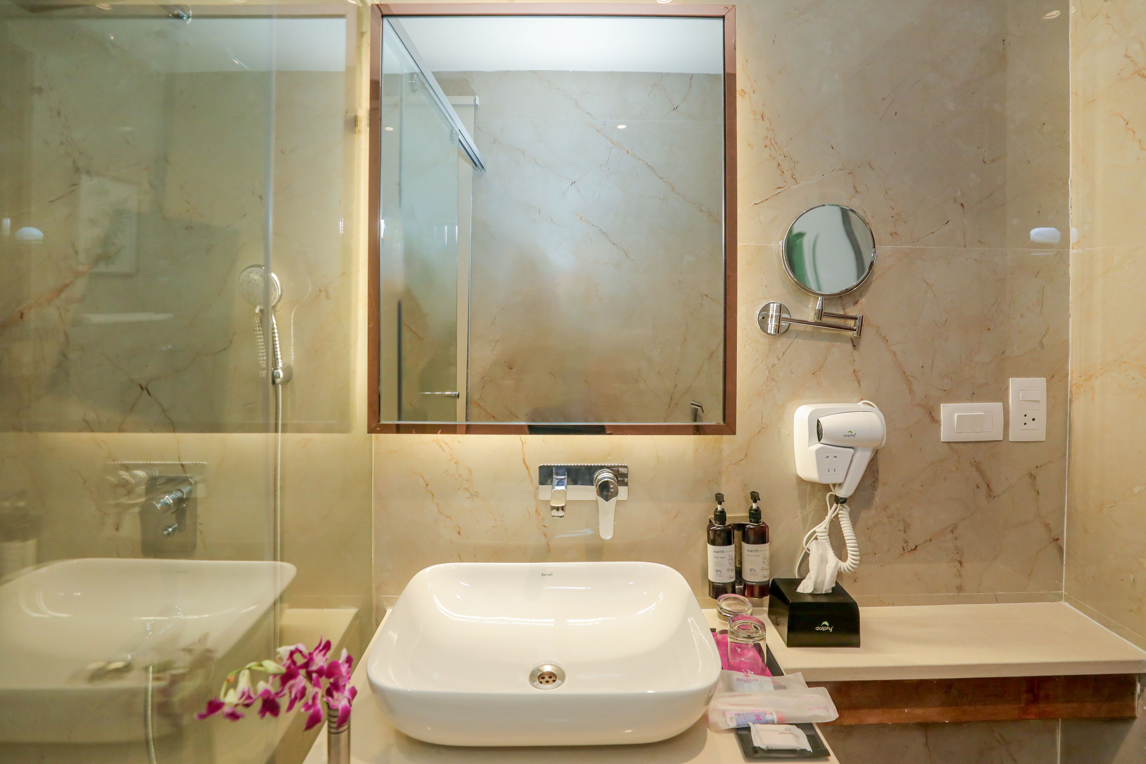 A bathroom with a large mirror, two sinks, a hairdryer, and a towel rack.